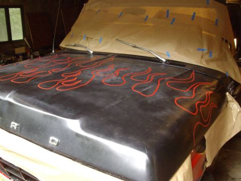 1978 Ford Bronco - The hood of a Ford vehicle is covered in red flame decals and masking paper is taped over the windshield.
