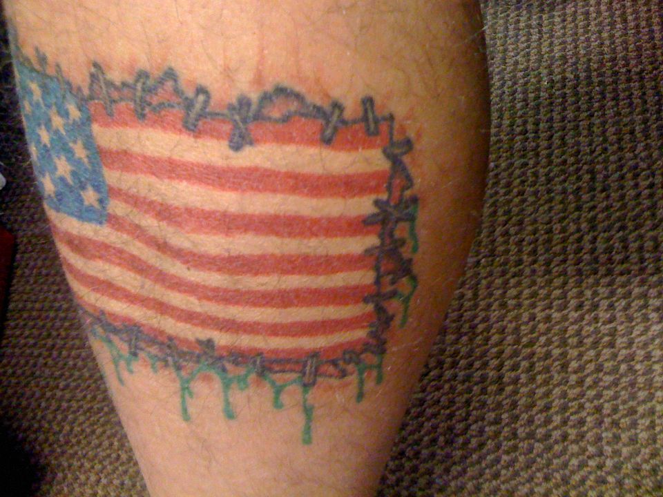 Tattoo of American flag with stitches and dripping green paint