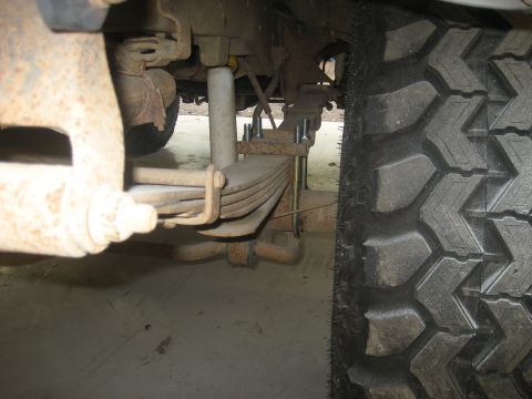 1978 Ford Bronco - A close-up view of a vehicle's suspension system and tire, showing rust and wear.