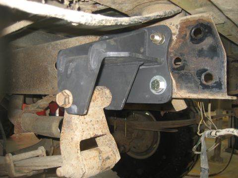1978 Ford Bronco - This image shows a close-up view of a suspension component, likely a bracket, attached to the frame of a vehicle, with leaf springs and oth…