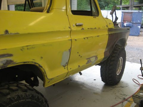 1978 Ford Bronco - This yellow pickup truck body shows signs of repair work, with primer and rust visible on its side panels.
