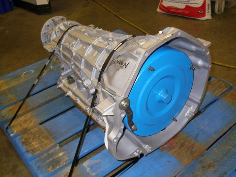 1990 Ford Bronco - Automatic transmission with a blue torque converter is strapped to a wooden pallet.