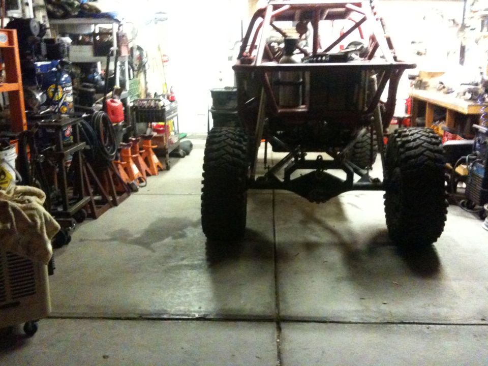 Off-road buggy rear axle and large tires in a garage with tools