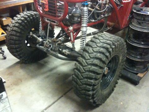 Suzuki Samurai - Close-up view of the front suspension and oversized tires on a custom red off-road buggy.