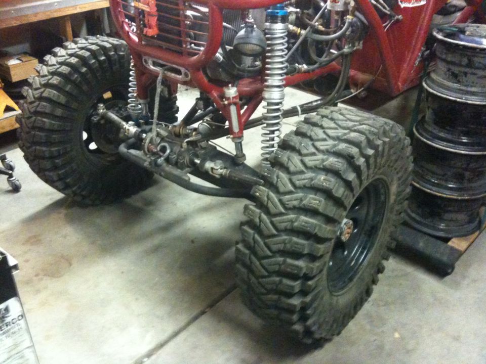 Red off-road buggy front suspension with large tires and custom roll cage
