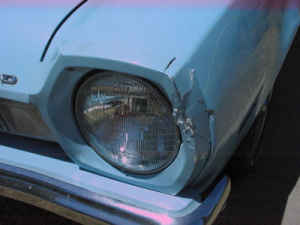 1972 Ford Pinto - Close-up of a car's front headlight and damaged fender.