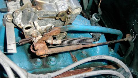 1979 Ford F-150 - Close-up view of carburetor linkage and springs on a blue engine block with visible CARQUEST wire.