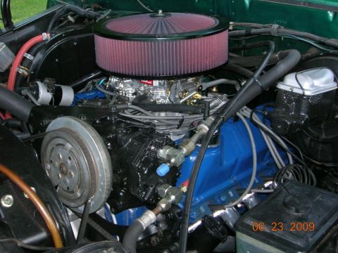 1979 Ford F-150 - The engine bay of a green 1979 Ford F-150 shows a prominent red air filter and carburetor assembly.