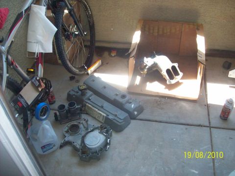 1985 Ford Bronco - Various engine components are spread out on the concrete floor, with a bicycle in the background.