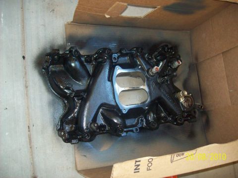 1985 Ford Bronco - A black intake manifold, likely for a Ford vehicle, is shown inside a cardboard box, possibly during a restoration or modification process.