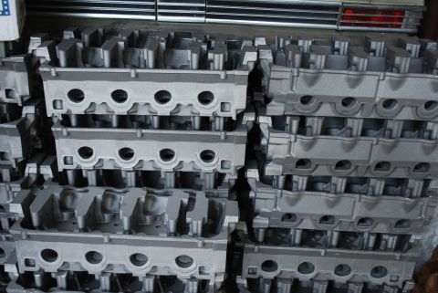 1969 Ford Fairlane - Multiple engine cylinder heads are stacked in a warehouse setting.
