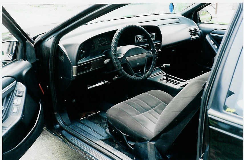 Interior shot of a 1990 Ford Thunderbird, showing the dashboard, steering wheel, seats, and gear shifter