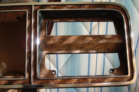 1979 Ford F-150 - Close-up of a vehicle's interior dashboard trim piece with a wood-grain finish and chrome accents.