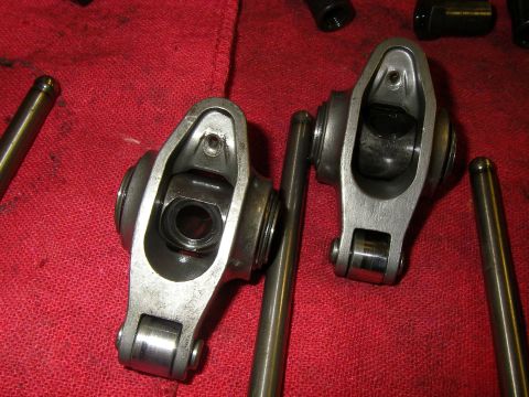1990 Ford Bronco - Two full roller rocker arms laid out on a red shop rag, showing the needle-bearing trunnion and roller tips at the valve end. Steel pushrod…