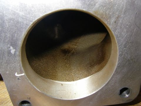 1990 Ford Bronco - Extreme close-up down the round throttle bore of an aluminum intake elbow, showing the ported and blended casting inside with a machined bo…