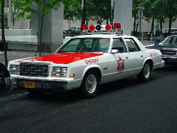 1991 Ford Crown Victoria - This older model sheriff's car has a distinctive light bar and "SHERIFF" markings on its side.