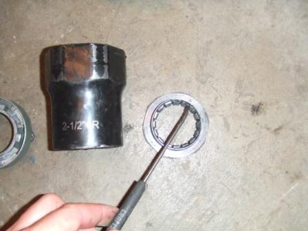 1996 Ford Bronco - A close-up shows a wheel bearing and a large socket, with a screwdriver pointing at the bearing.