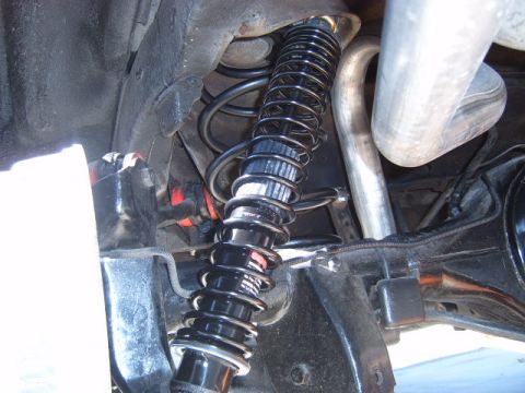 1973 Ford Ranchero - Close-up view of a vehicle's rear suspension system, showing a shock absorber and exhaust pipe.
