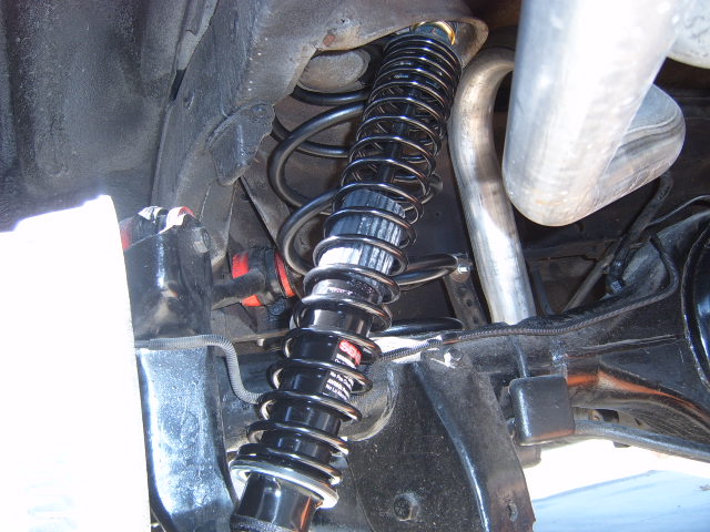 Black coilover shock absorber with silver spring and exhaust pipe