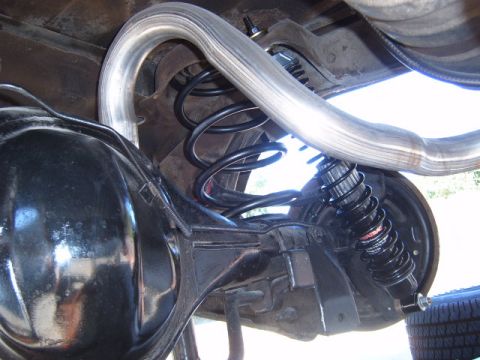1973 Ford Ranchero - Close-up view of the rear suspension components and exhaust system, including a coil spring and shock absorber.
