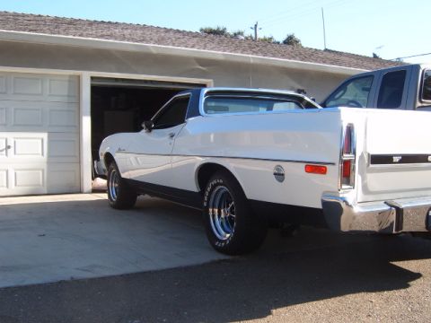 1973 Ford Ranchero - A white coupe utility with a dark roof is parked in a driveway next to an open garage door.