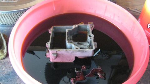 1968 Ford Ranchero - Carburetor parts submerged in cleaning fluid inside a pink tub.