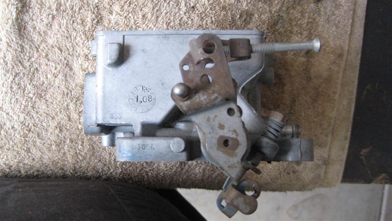 carburetor with linkage and adjustment screw visible, some rust on metal parts