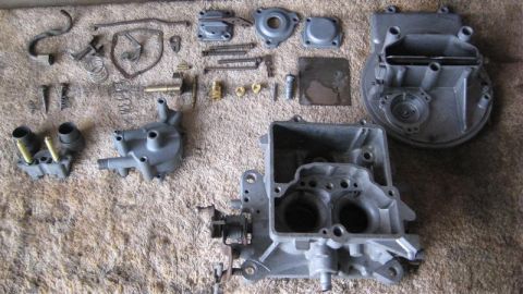 1968 Ford Ranchero - A collection of disassembled carburetor components are spread out on a carpeted surface.