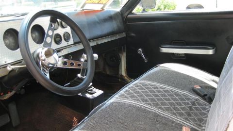1968 Ford Ranchero - The interior of a car shows a custom steering wheel and a diamond-patterned seat cover.
