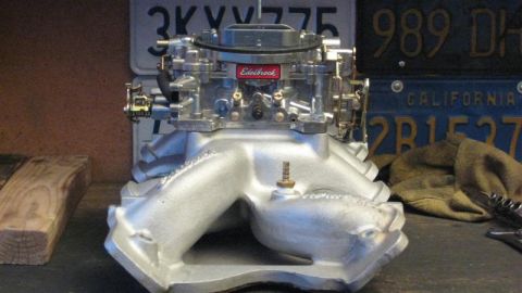 1968 Ford Ranchero - Close-up of an Edelbrock carburetor and intake manifold assembly, with license plates visible behind.