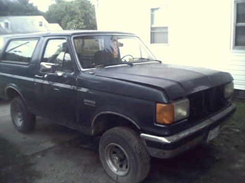 1989 Ford Bronco - This Ford Bronco is parked in a driveway next to a house.