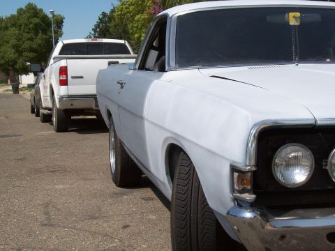 1968 Ford Ranchero - A white 1968 Ford Ranchero is parked on a street, with a white pickup truck behind it.