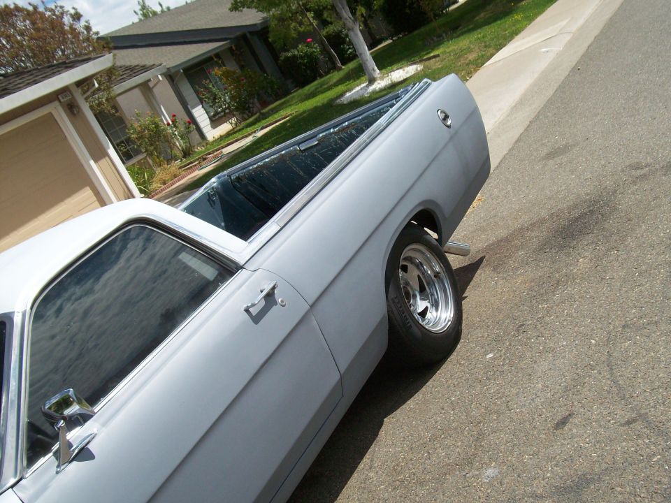 Low-angle side view of gray classic car with chrome mirror and polished wheel on a street.