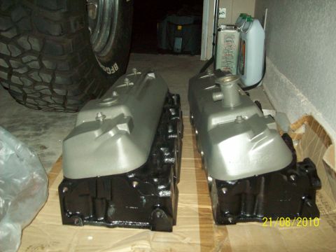 1985 Ford Bronco - Two engine cylinder heads are displayed, with a large tire visible in the background.