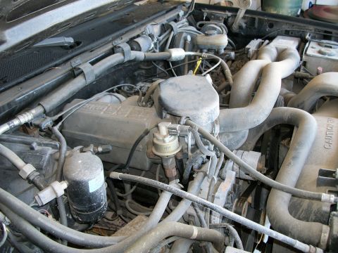 1990 Ford Bronco - A close-up view of the engine compartment, showing various mechanical parts and wiring.
