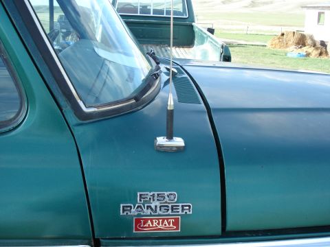 1979 Ford Bronco - Close-up of a green truck's fender shows F-150 Ranger Lariat badging and an antenna.