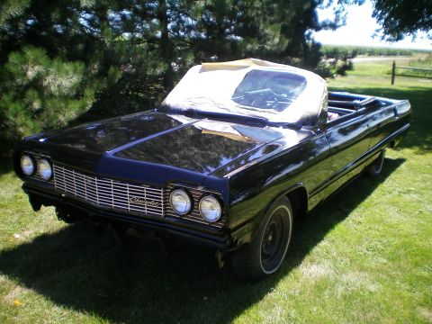 1964 Chevrolet Impala - A black 1964 Chevrolet Impala convertible sits on a grassy lawn under a sunny sky.