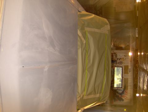 1964 Chevrolet Impala - A car body is prepped and taped off inside a spray booth, ready for painting.