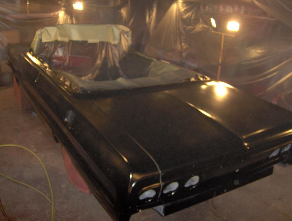 Black 1964 Chevrolet Impala convertible with masked windows, viewed from the front 3/4 angle in a workshop