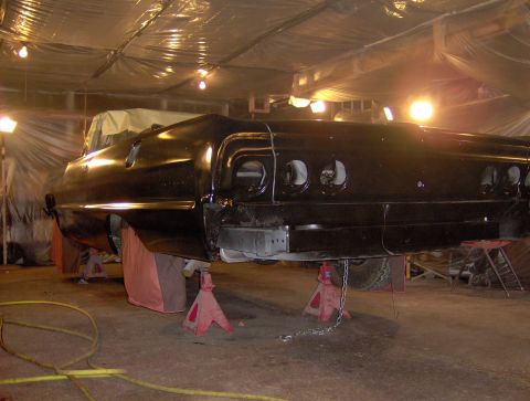 1964 Chevrolet Impala - The rear section of a black 1964 Chevrolet Impala is elevated on jack stands, indicating it is in a restoration or repair process.