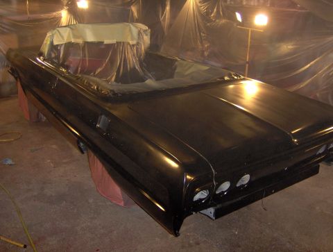 1964 Chevrolet Impala - A black 1964 Chevrolet Impala convertible is shown from the rear, with its interior covered, during a paint job.