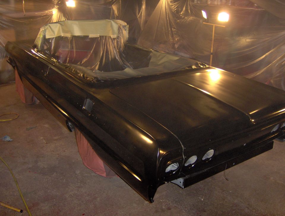 Black 1964 Chevrolet Impala convertible rear view, interior covered for paint
