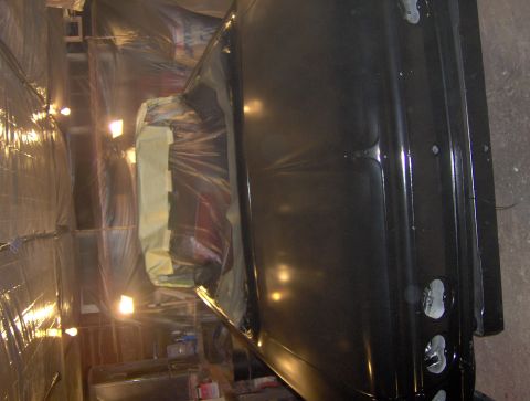 1964 Chevrolet Impala - A car body is being prepped for painting inside a makeshift booth.