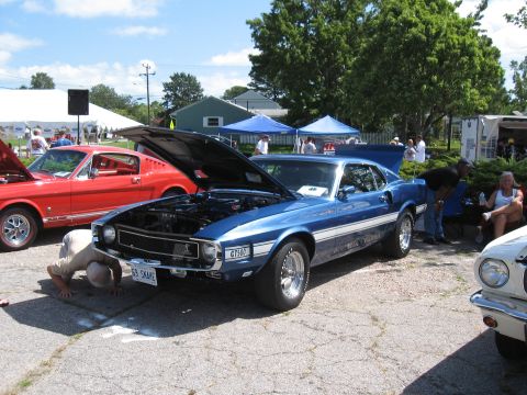 1968 Shelby GT500 - A blue 1969 Shelby GT500 is displayed with its hood open at a car show, alongside other vehicles.