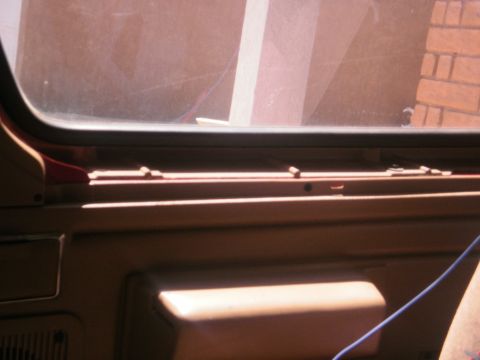 1991 Ford Bronco - Close-up of a vehicle's interior door panel, showing the armrest and window trim.