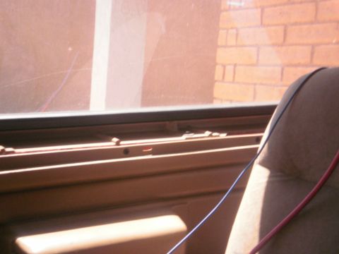 1991 Ford Bronco - Interior view of a vehicle showing tan door panel and seat, with a brick wall outside.