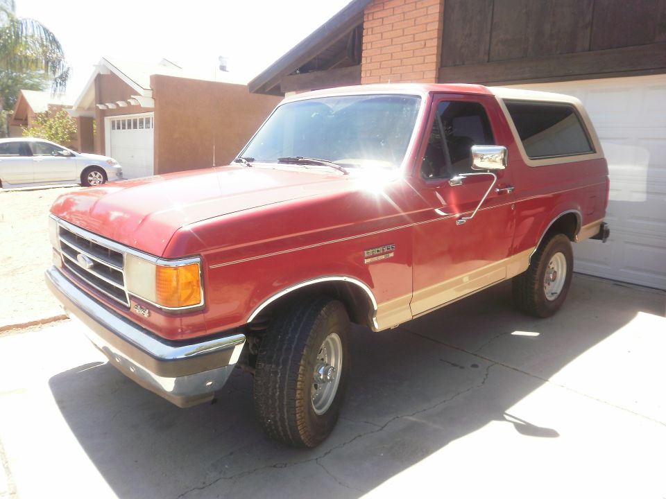 1991 Ford Bronco parked in driveway, red with tan trim