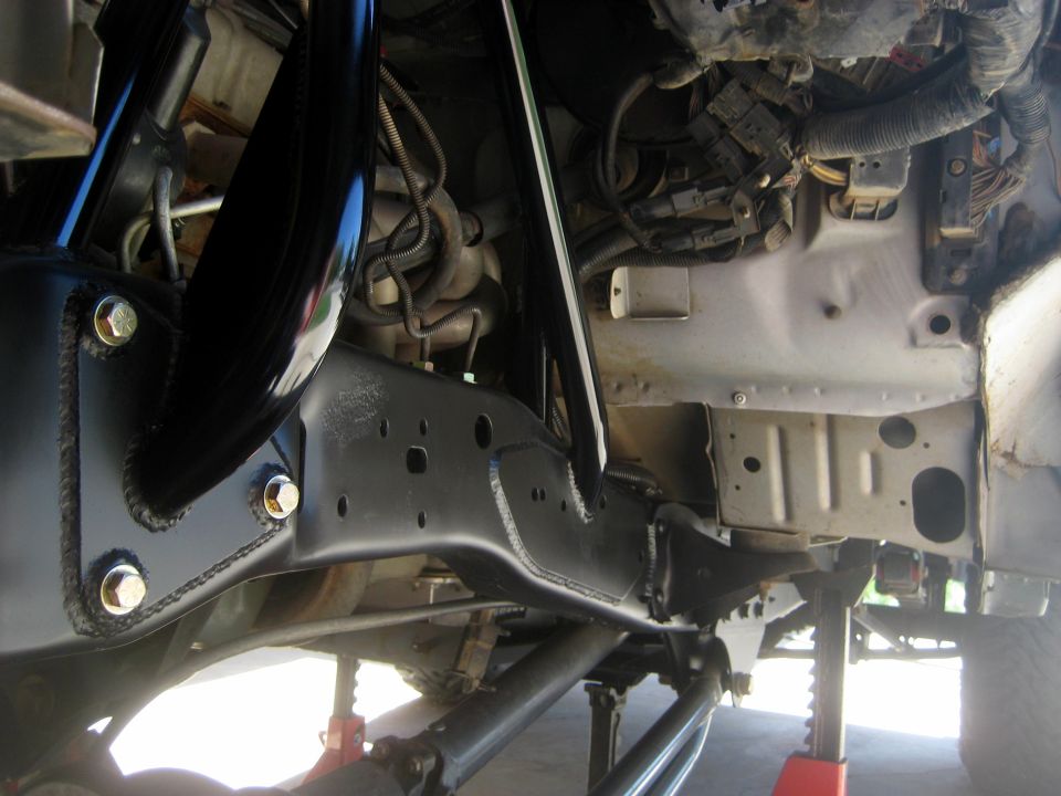 Black painted frame section with gold bolts, suspension parts, and engine wiring