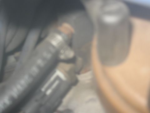 1994 Ford Bronco - A close-up view of engine components, including hoses and a coolant reservoir, with some text visible on a hose.