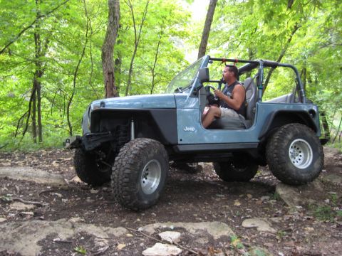 2005 Jeep Wrangler - Man driving a blue 2005 Jeep Wrangler TJ on a rocky off-road trail.